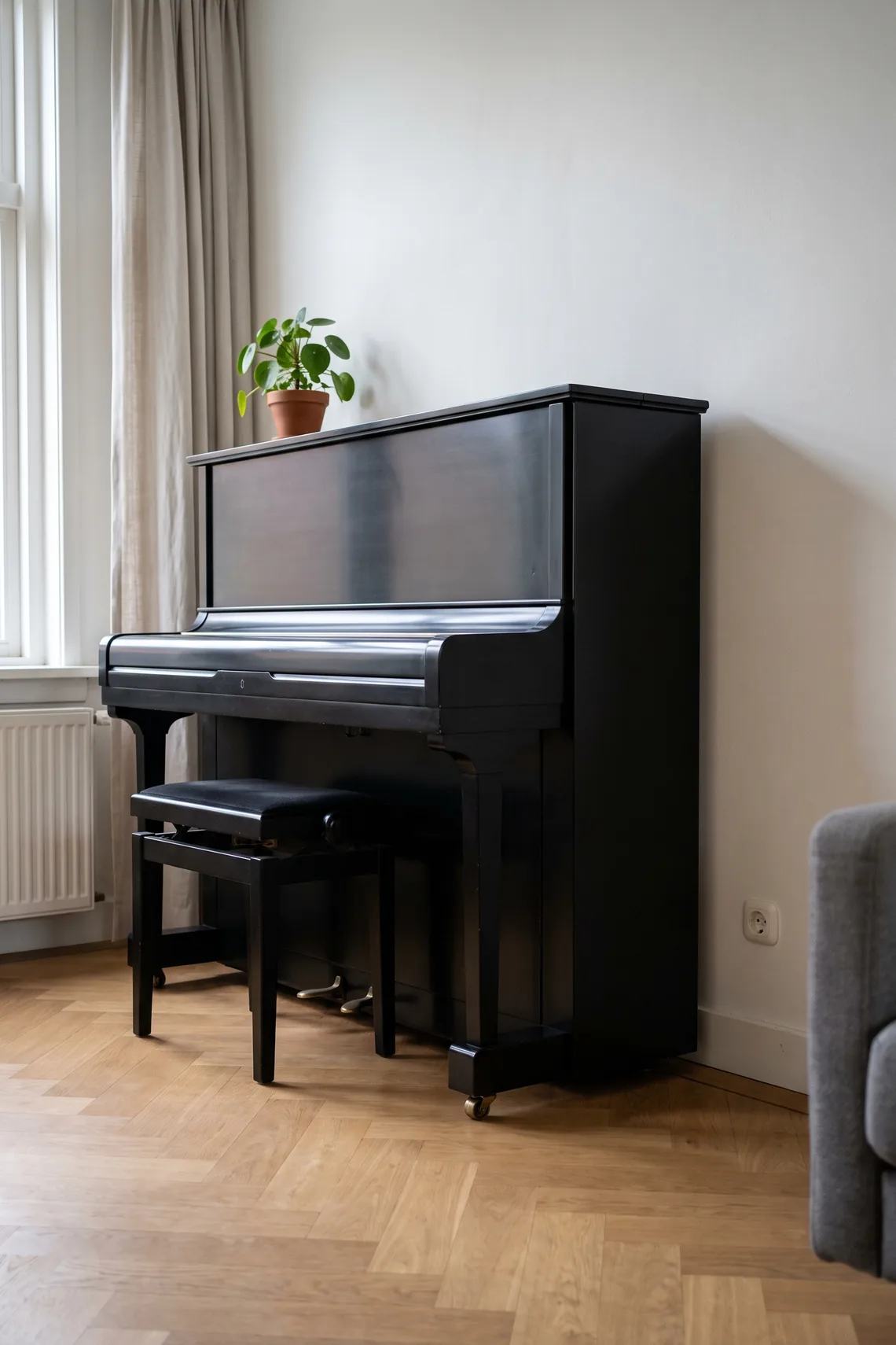 Een rechte piano tegen de wand van een woonkamer, schuin van opzij.