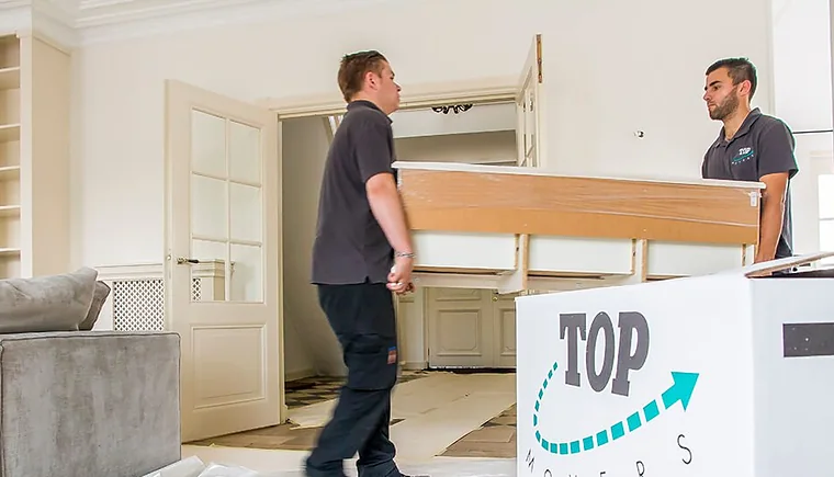 Twee verhuizers van Top Movers dragen samen een kast