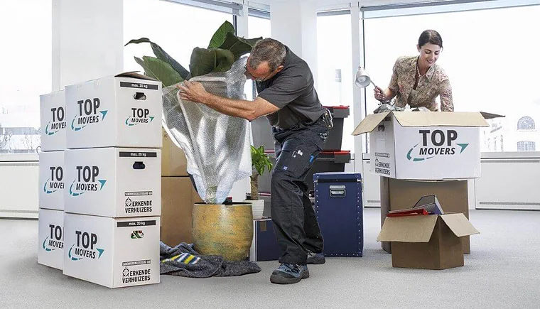 Verhuizer van Top Movers pakt een plant in, tussen verhuisdozen van Top Movers
