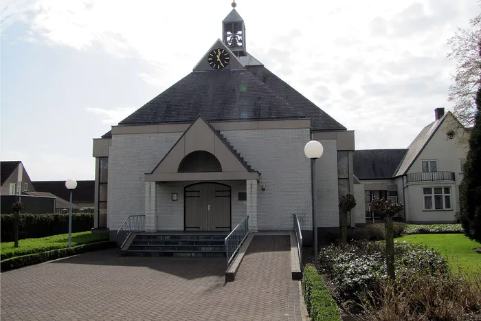 Voorgevel van de Sint-Odakerk in Ysselsteyn, met een klokkentorentje op het dak en een bestraat voorplein