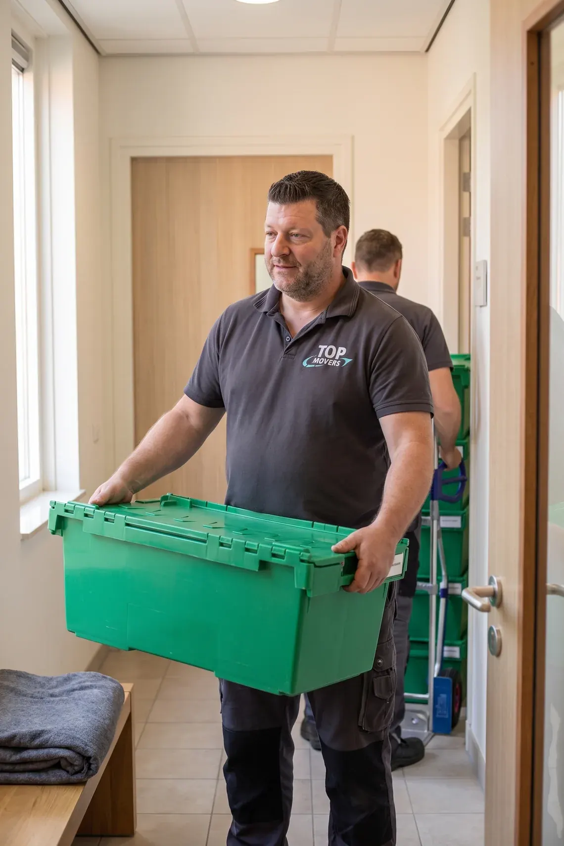 Verhuizer draagt een groene verhuiskrat door de gang van een gezondheidscentrum